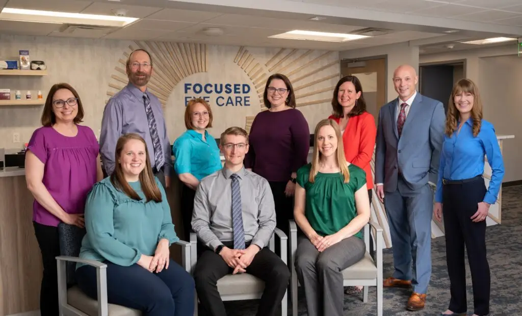 Focused Eye Care team pose and smile together in office lobby