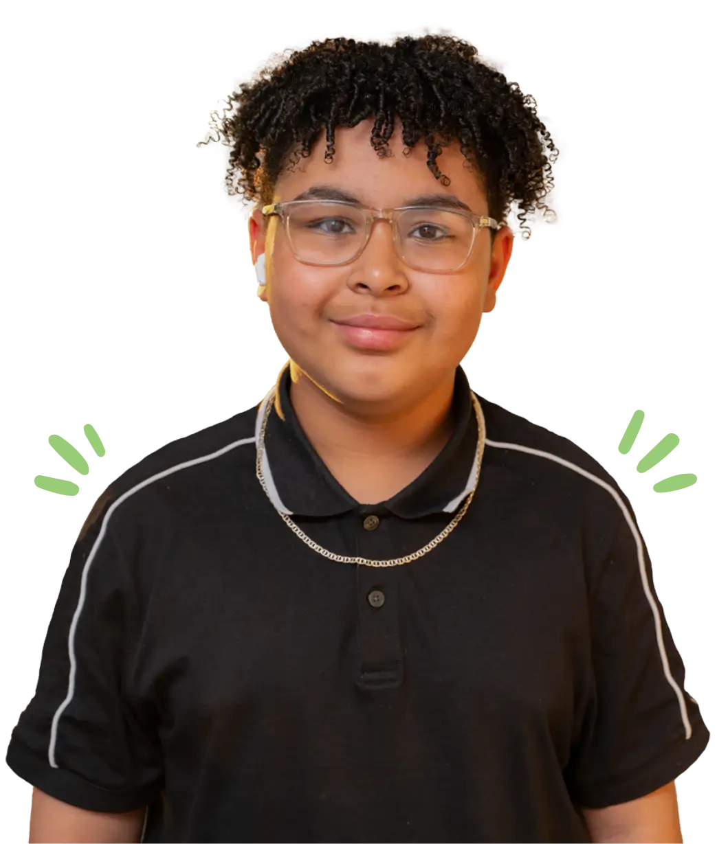 Smiling teenager with glasses and earbuds, wearing a black polo shirt and a chain necklace.