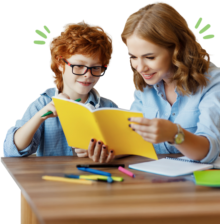 A woman and a boy smiling while reading a yellow book together at a table with colorful pens.
