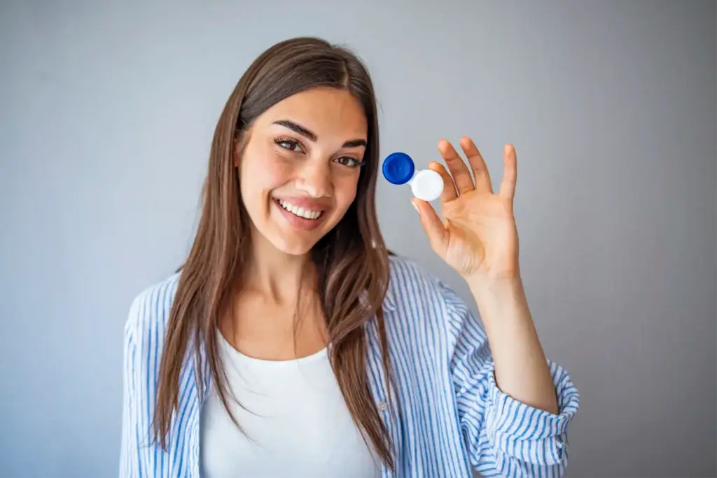 A smiling woman holding an open contact lens case.